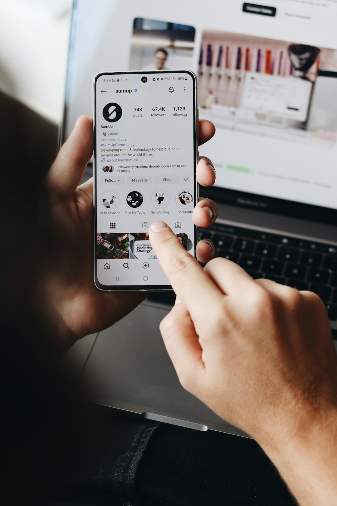 A person is holding a smartphone and browsing the SumUp Instagram profile.